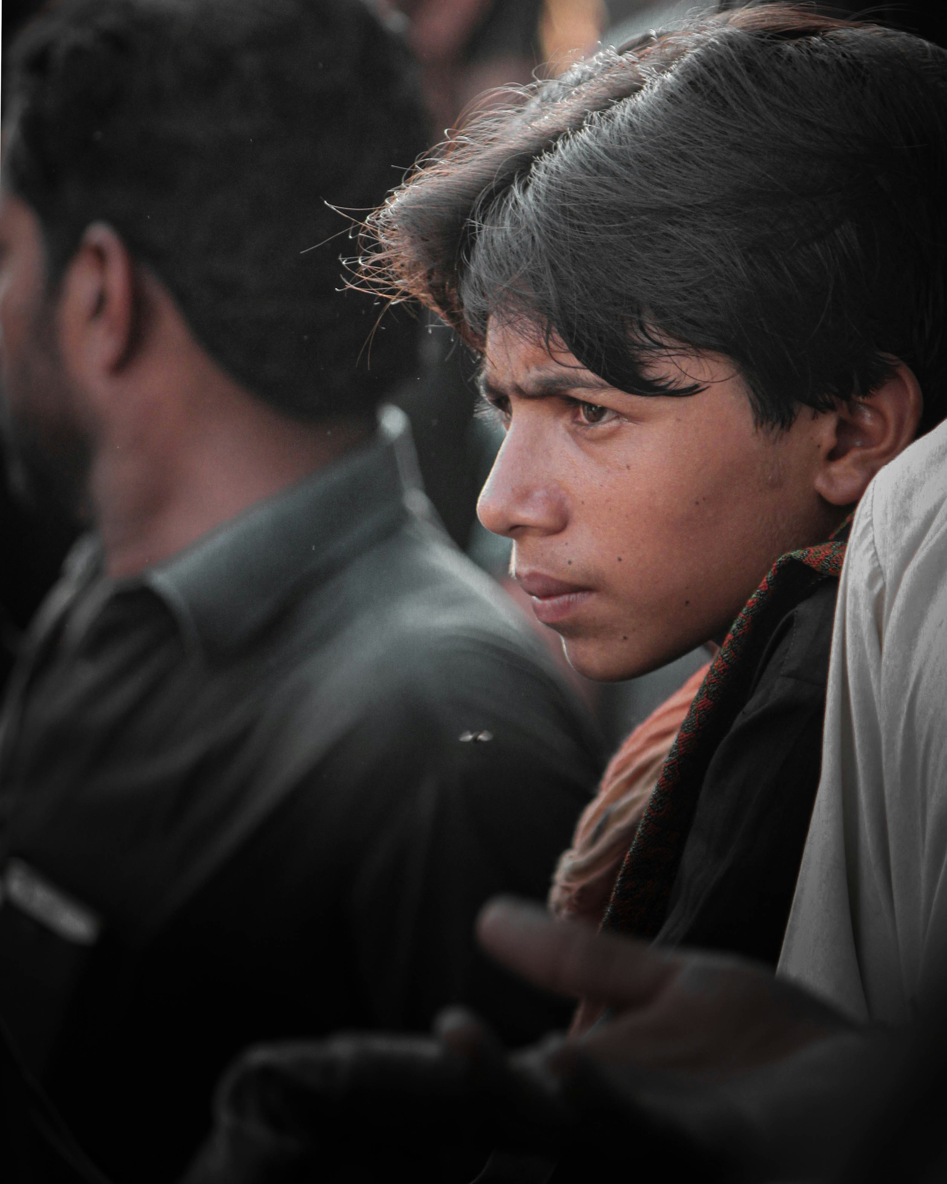 A young boy sitting in a crowd of people photo – Free Portrait Image on ...