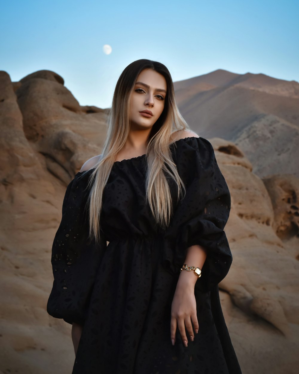 a woman in a black dress standing in the desert