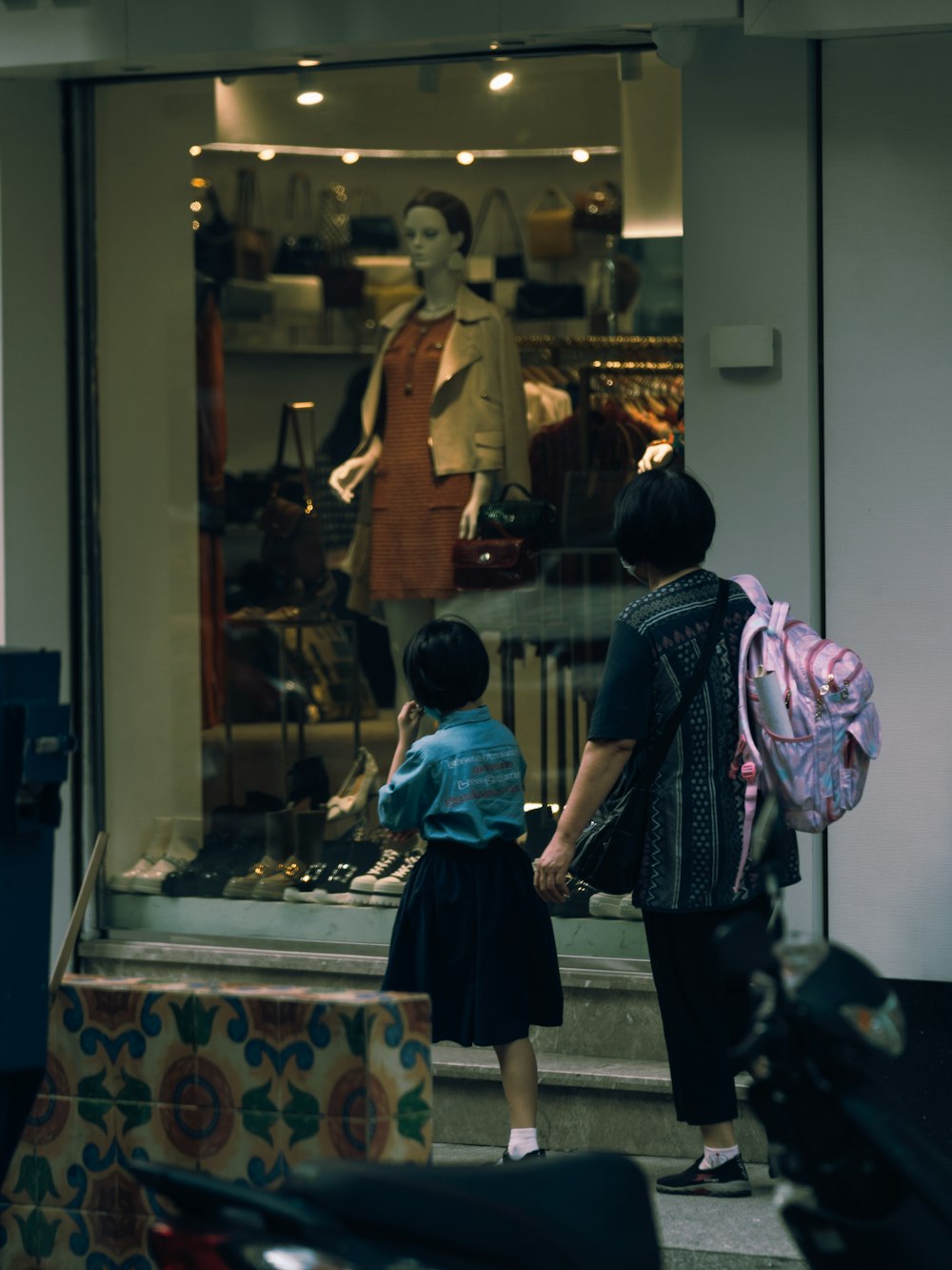 a woman and a child standing in front of a store window