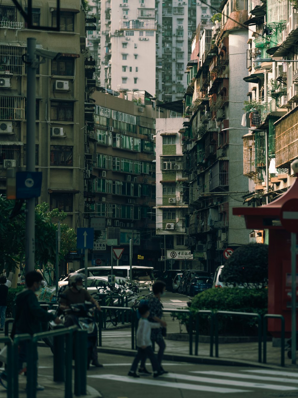 a group of people walking down a street next to tall buildings