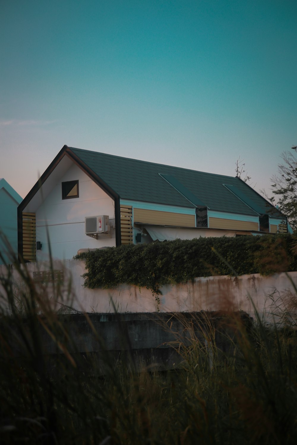 a white house with a black roof and a green roof