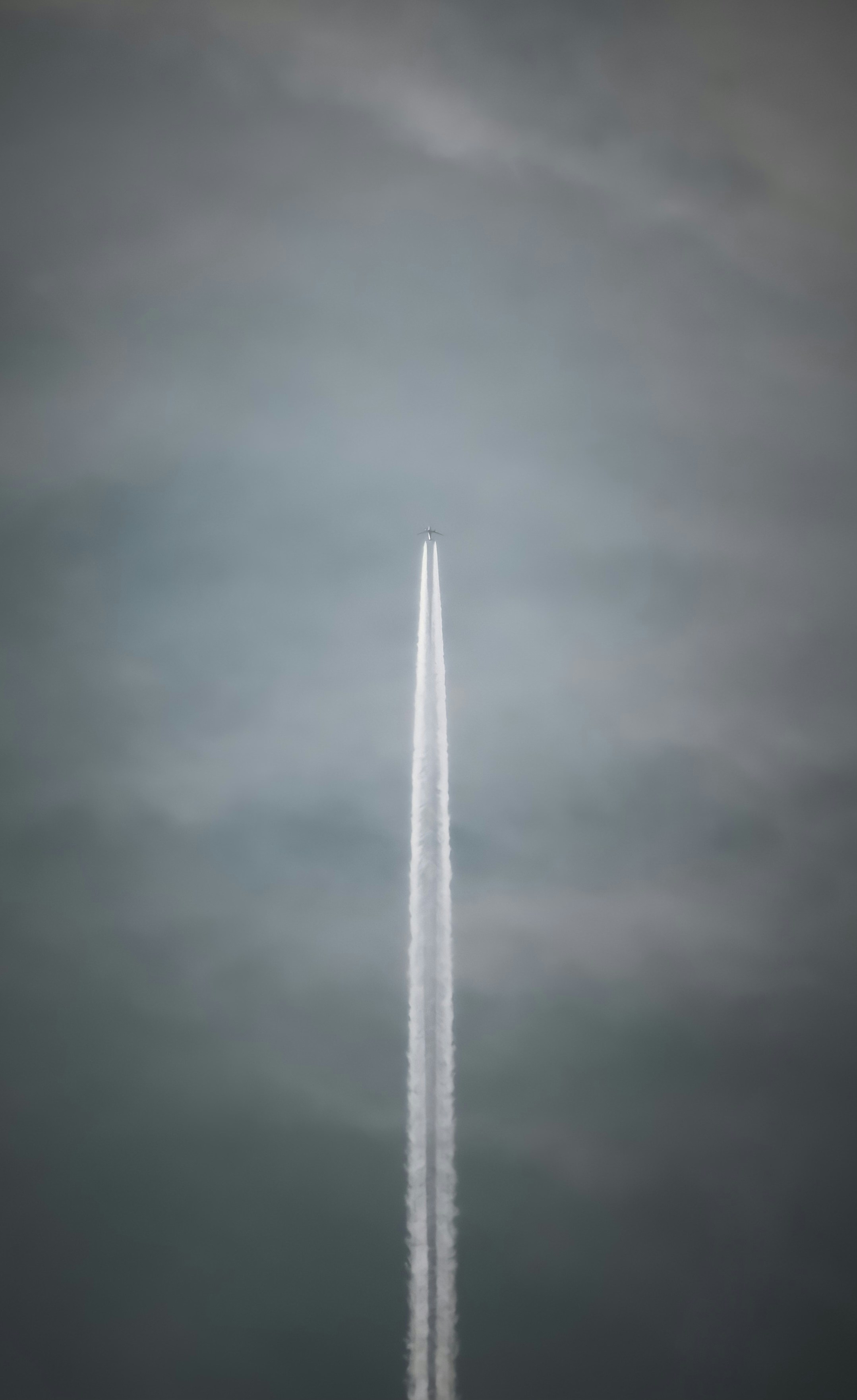 a jet flying through a cloudy sky leaving a trail of smoke