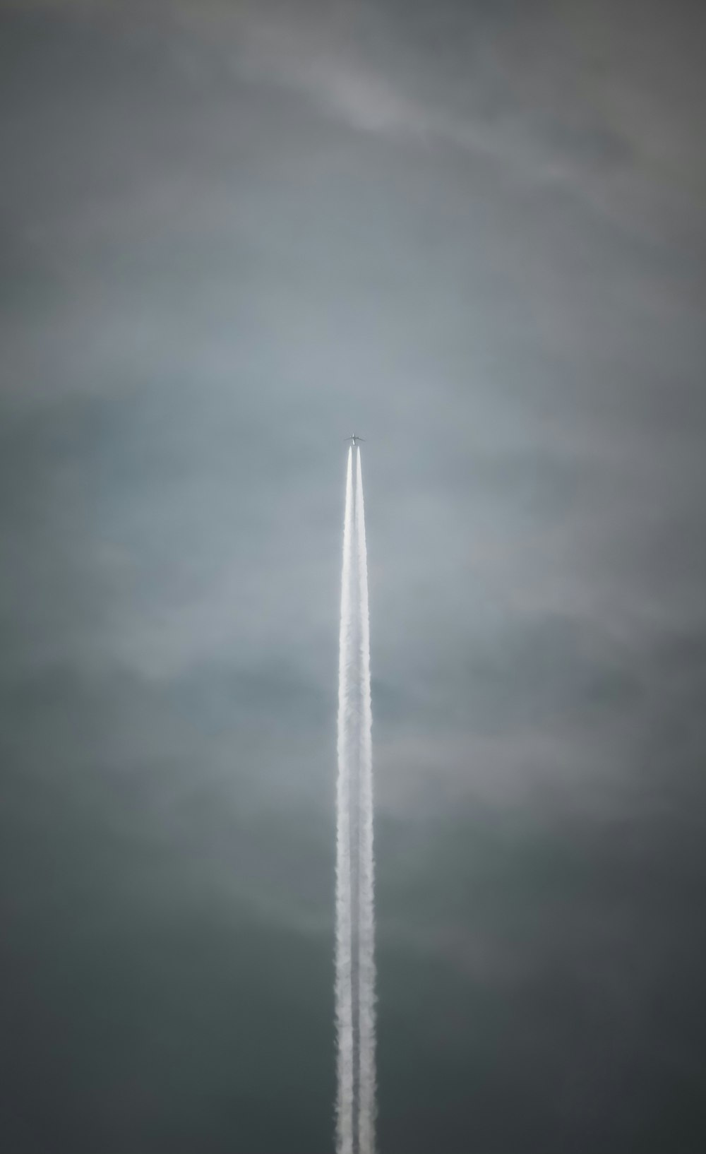 a jet flying through a cloudy sky leaving a trail of smoke