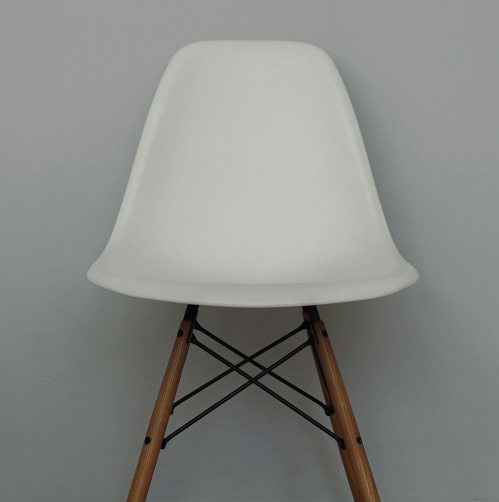 a white chair with wooden legs against a gray wall