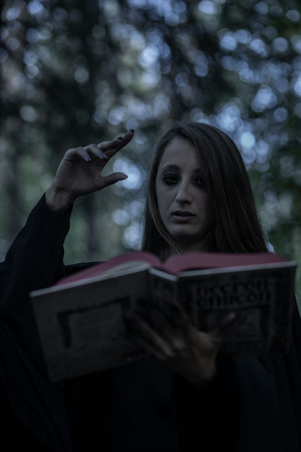 a woman reading a book in a dark forest