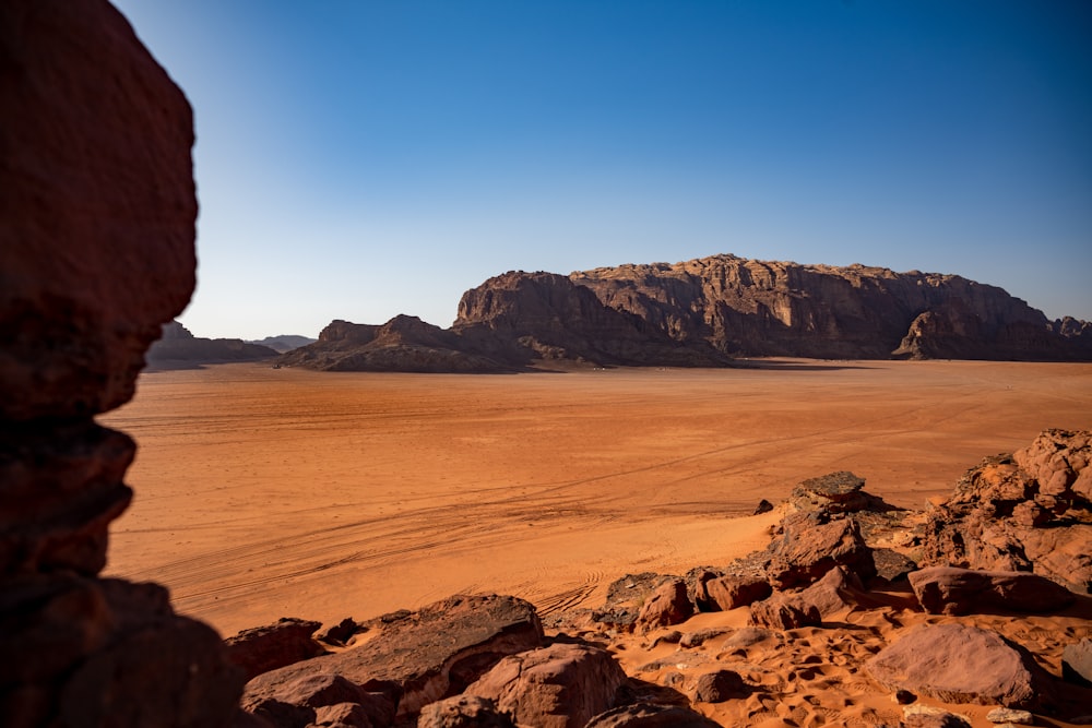 a view of a desert with rocks and a mountain in the background
