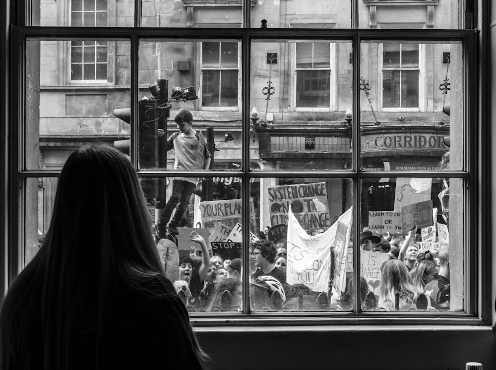 a woman looking out a window at a protest