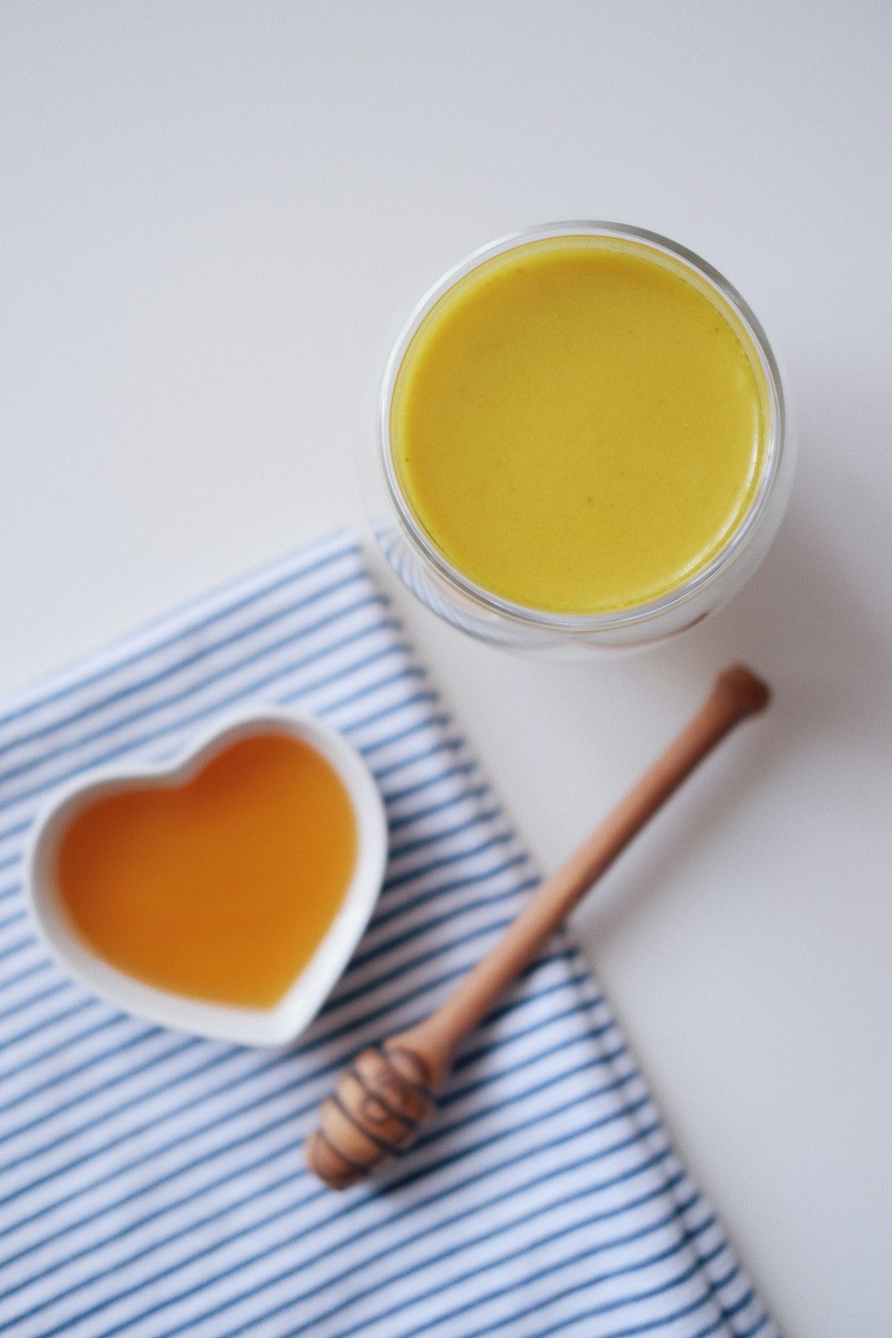 a bowl of honey and a spoon on a blue and white towel