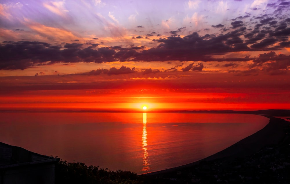 a sunset over a body of water with clouds in the sky