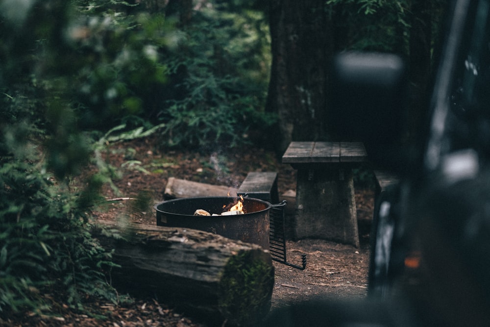 a black truck parked in a forest next to a fire pit