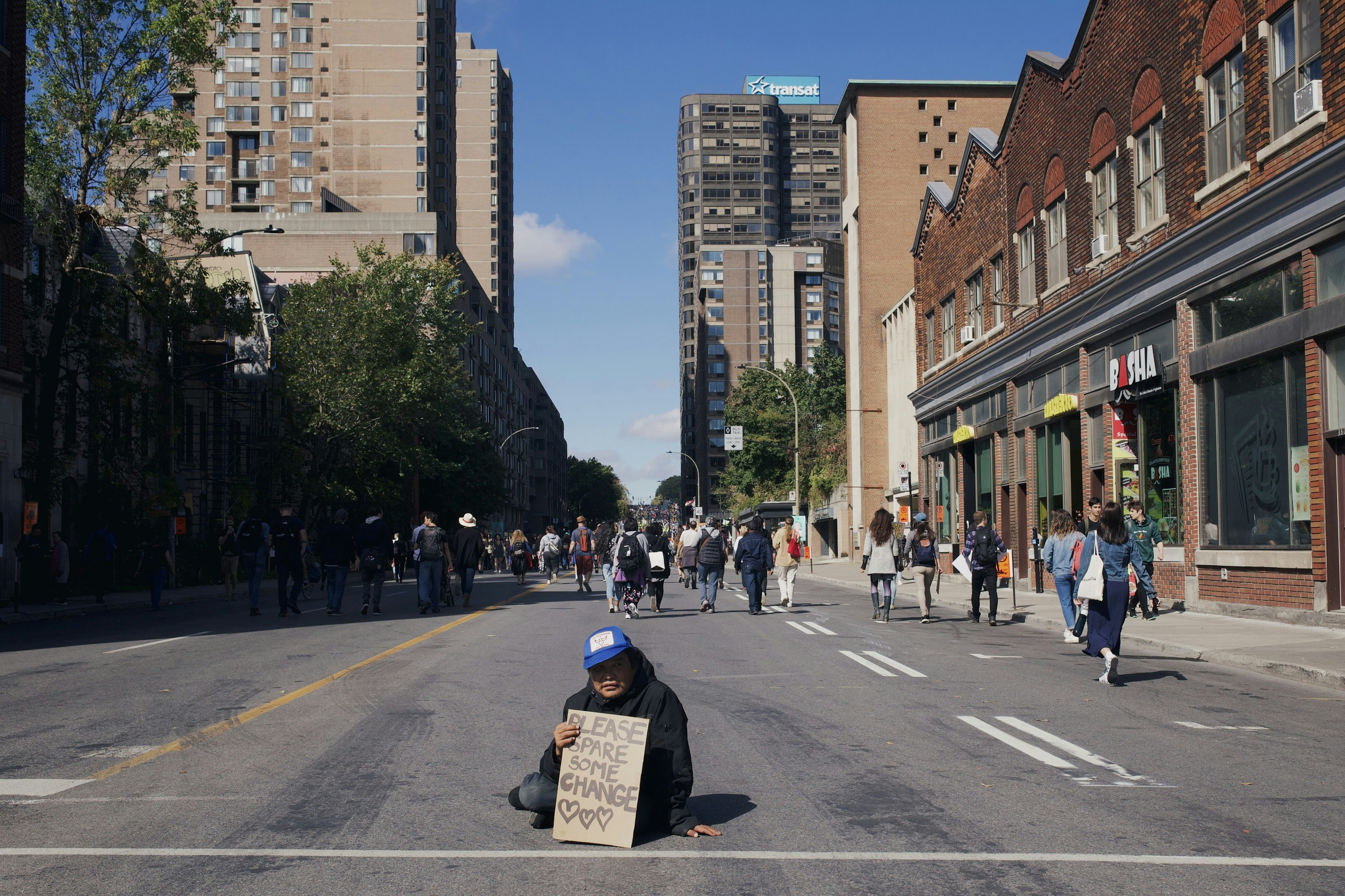a person sitting in the middle of a street holding a sign