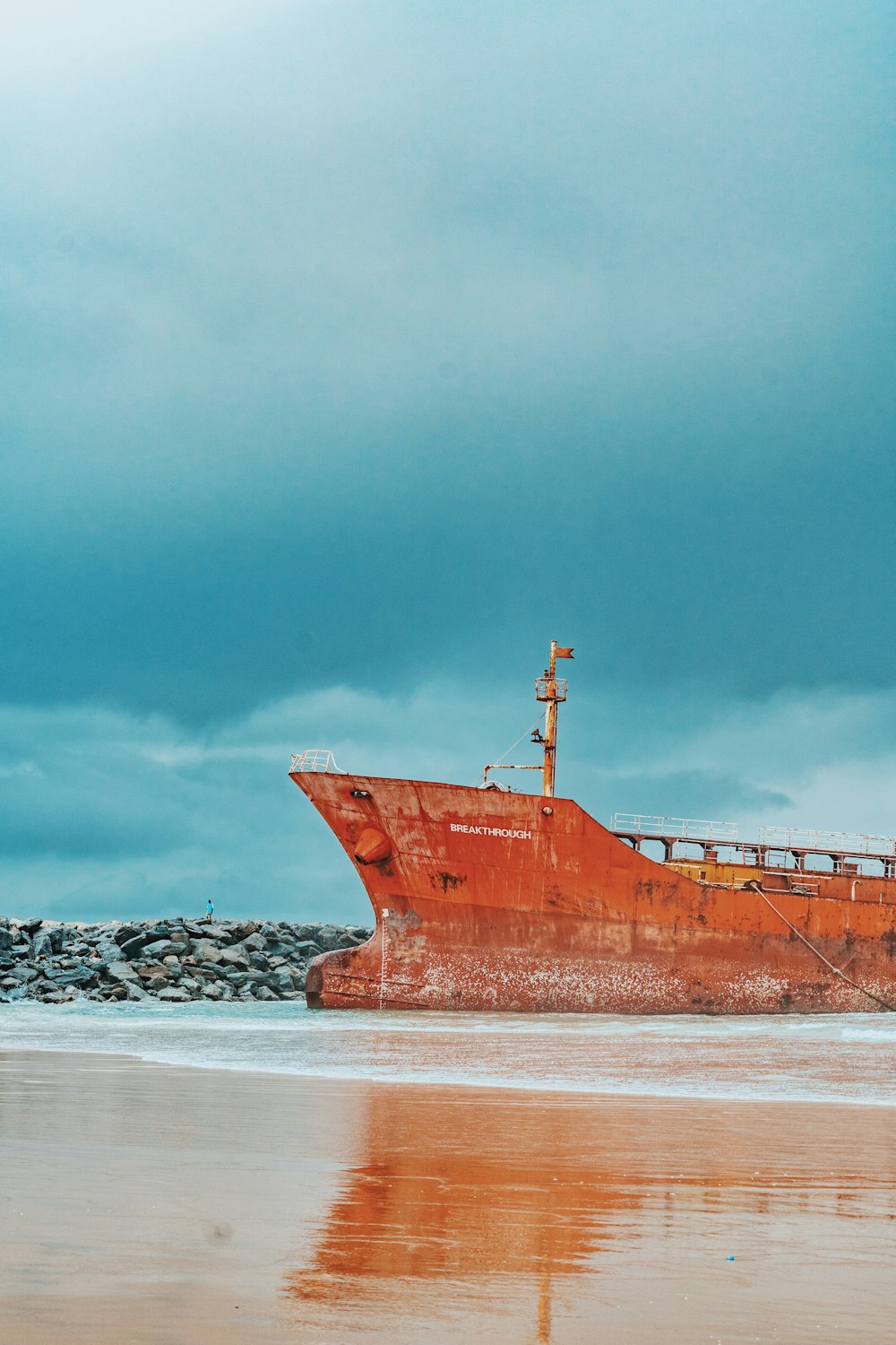 a large rusted ship sitting on top of a sandy beach