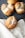 A set of freshly baked bread rolls are sprinkled with coarse salt. They are resting on a dark ridged baking tray, with one roll placed on a beige cloth beside the tray. The texture of the bread is golden brown with a crusty exterior, and the background features a soft fabric.