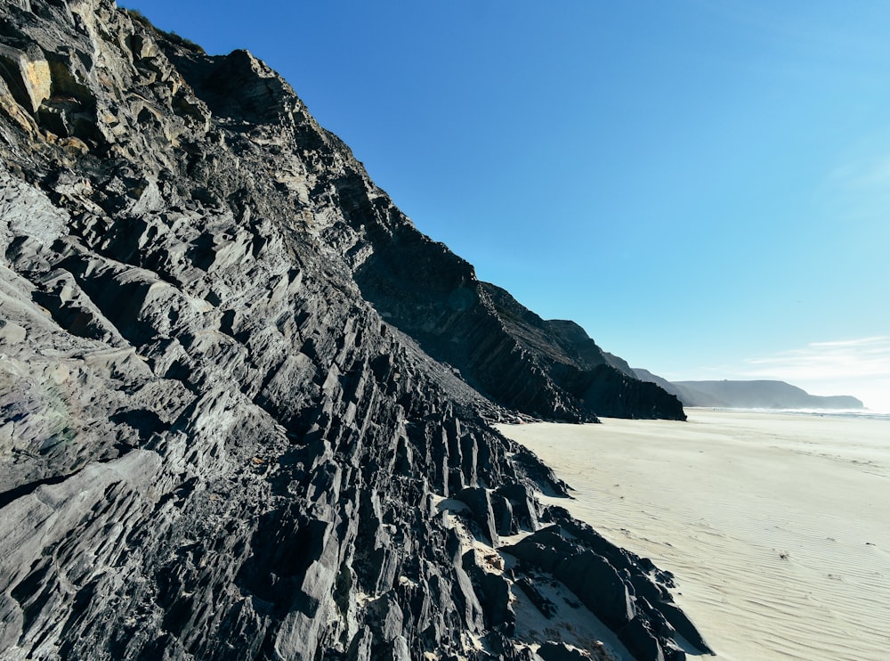 a rocky cliff on a beach with a blue sky