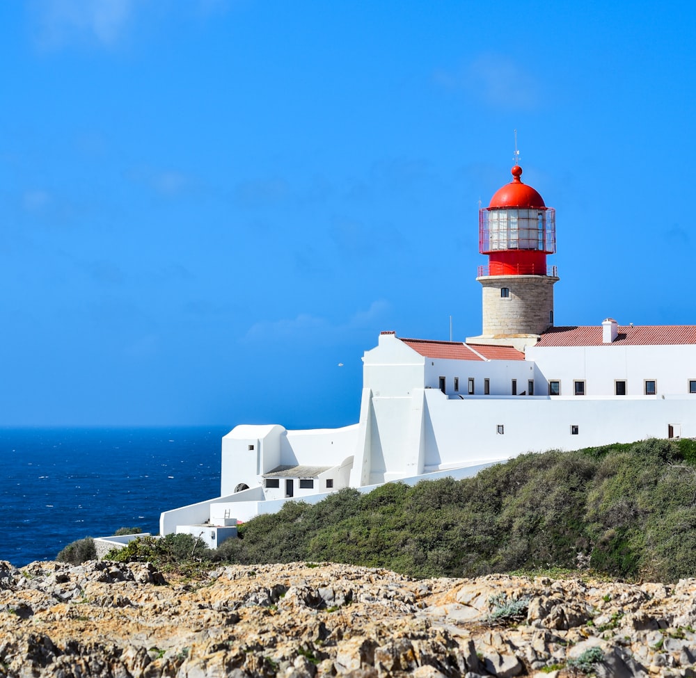 a red and white lighthouse sitting on top of a cliff