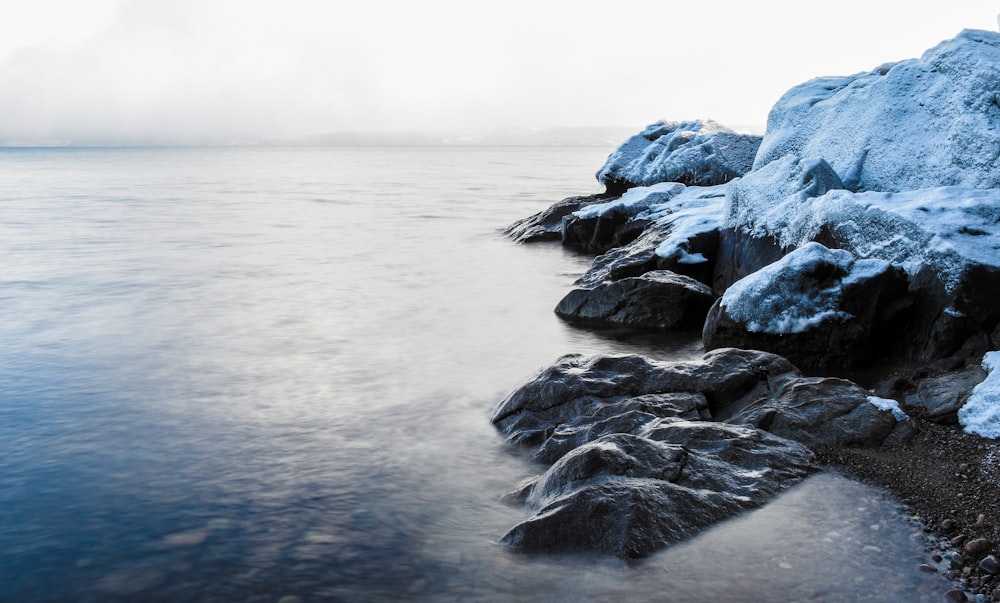 a body of water surrounded by snow covered rocks