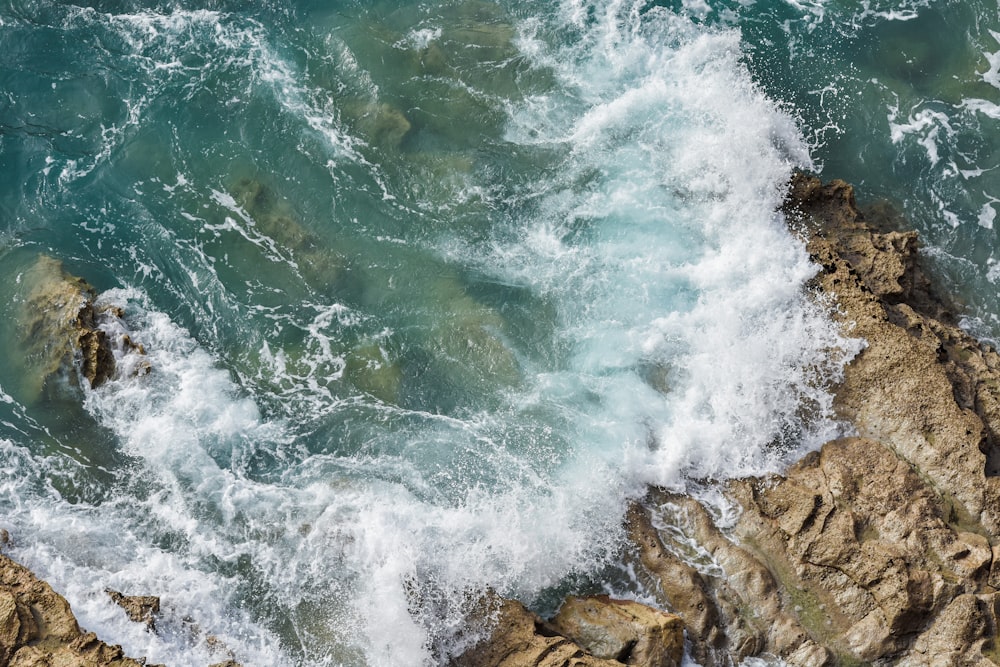 an aerial view of the ocean waves crashing on the rocks