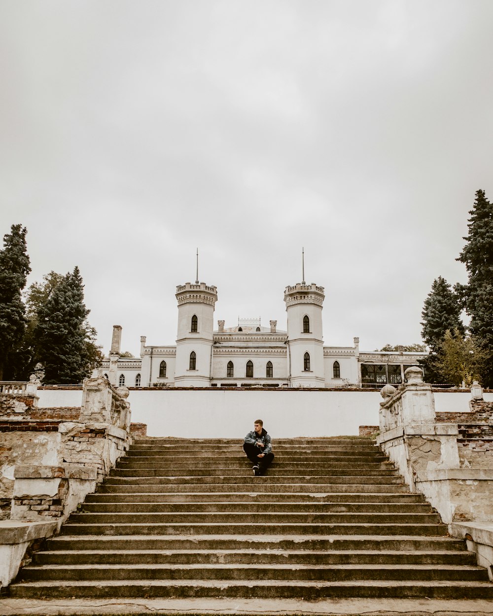 a man sitting on a set of stairs in front of a castle