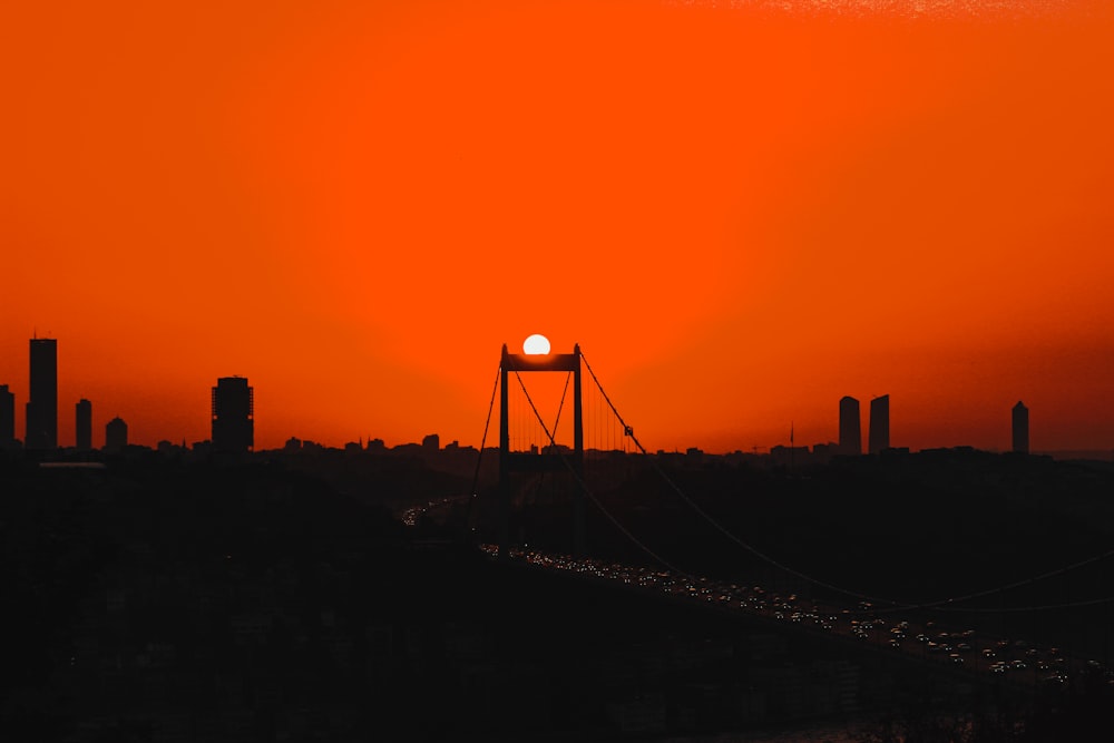 the sun is setting over a bridge in a city