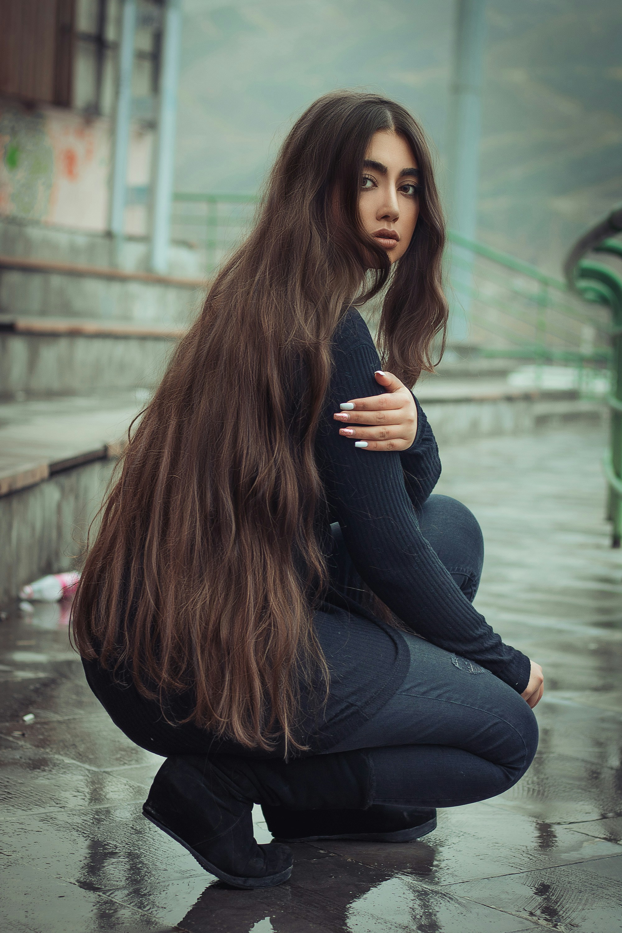 Woman with very long, voluminous dark hair sitting on outdoor steps.