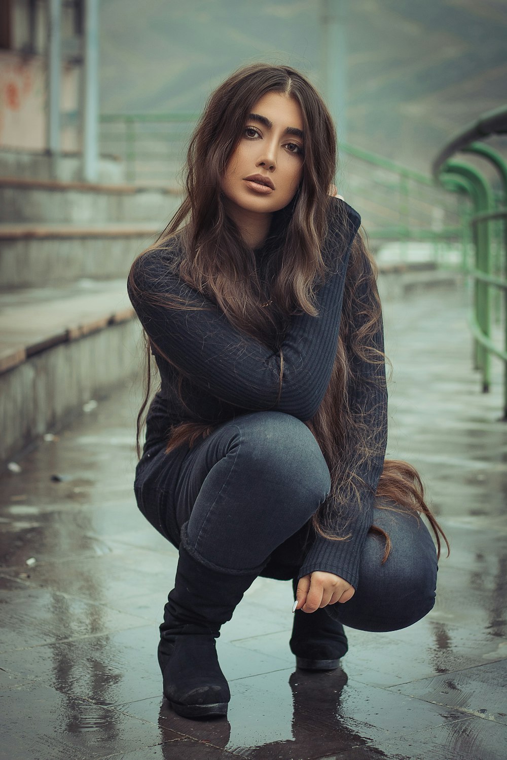 a woman kneeling down on the ground in the rain