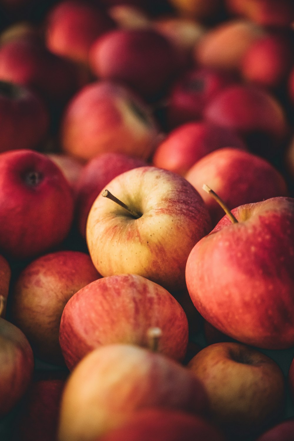 a pile of red and yellow apples sitting on top of each other