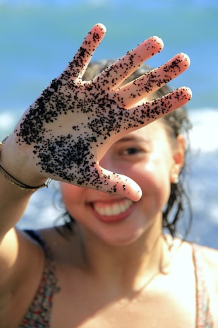 A happy customer holding a sand can with a bright smile, standing by the ocean.