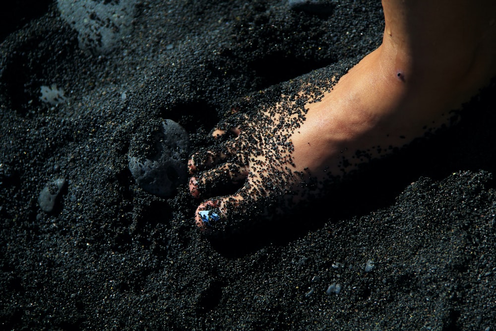 a person's bare foot covered in black sand