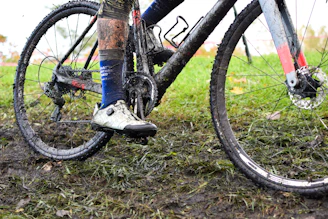 Close-up of a cyclist's muddy tires spinning on a rocky gravel path during a challenging ride.