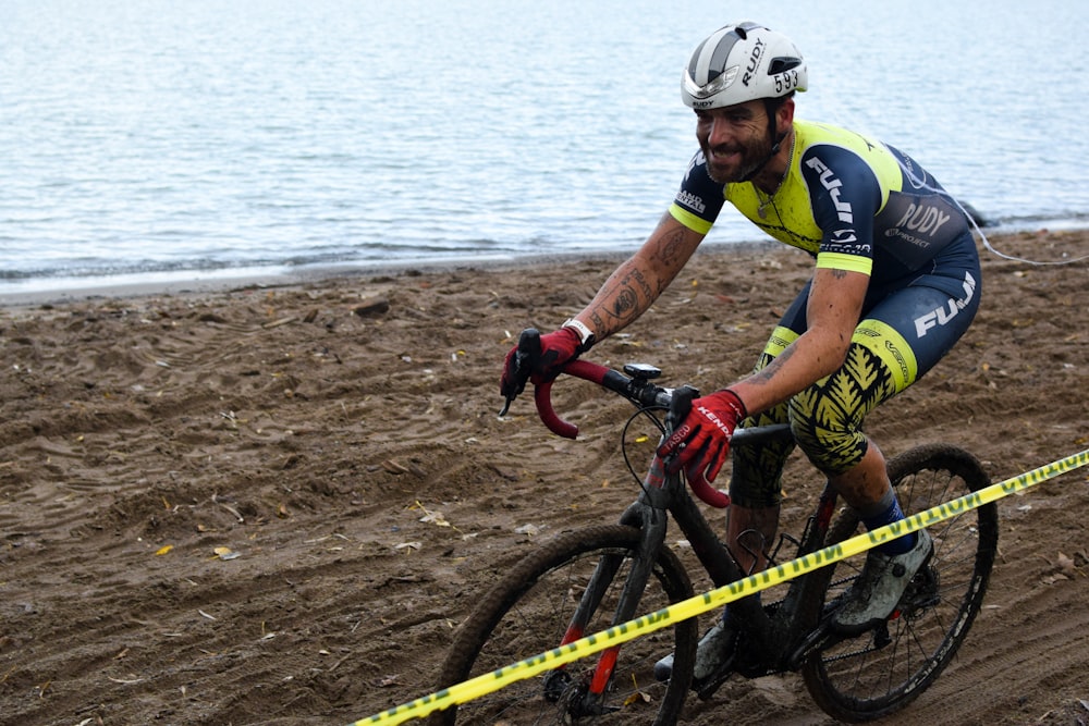 a man riding a bike on top of a sandy beach