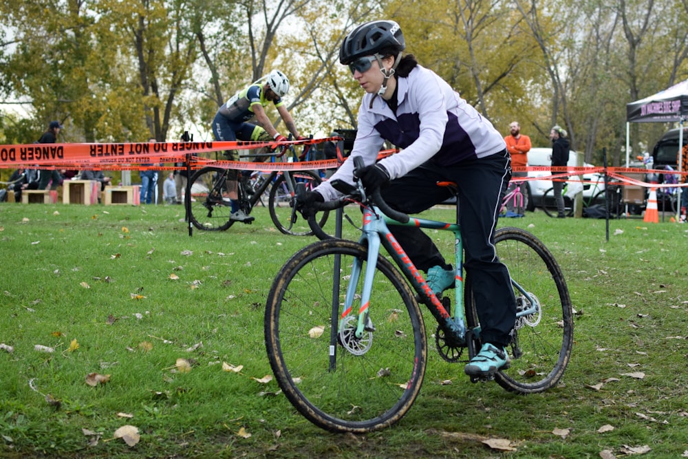 a woman riding a bike down a lush green field