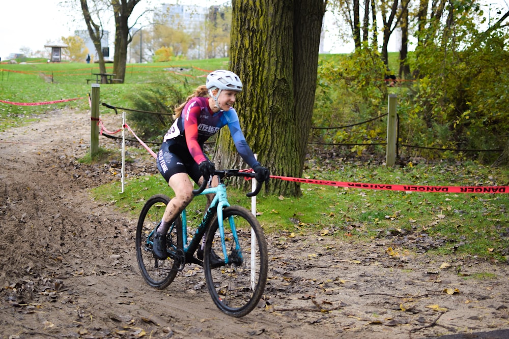 a woman riding a bike down a dirt road