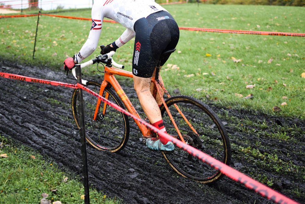 a man riding a bike down a muddy road