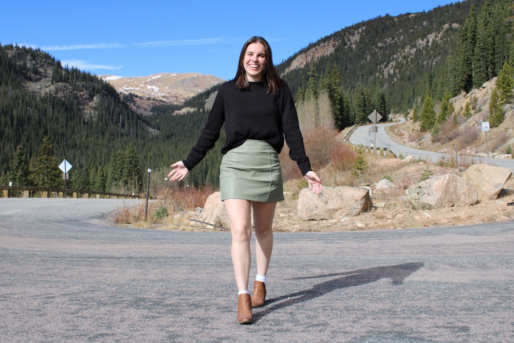 a woman walking down a road in the mountains