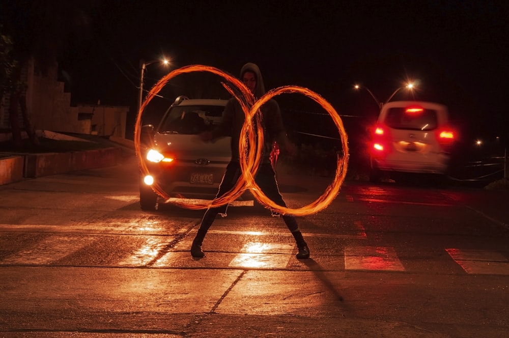 a man holding two fire hoopes in front of a car