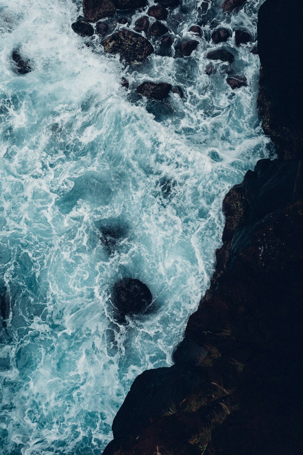 a person standing on a rock next to a body of water