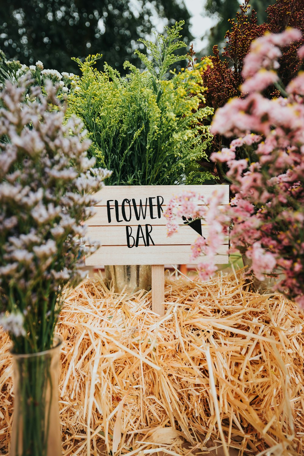 a flower bar sign sitting on top of a pile of hay