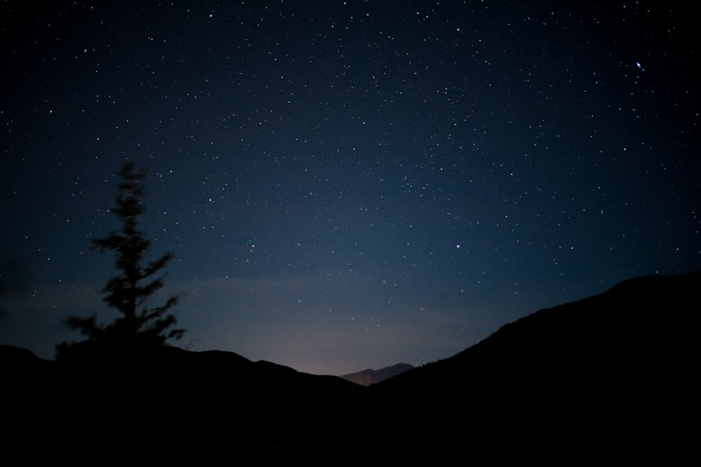 the night sky with stars above a mountain range