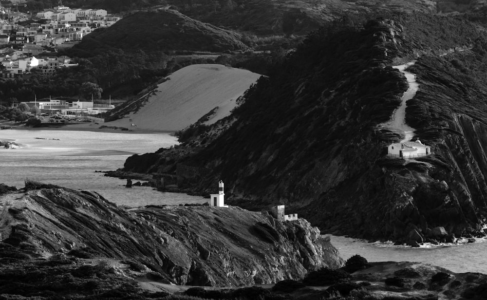 a black and white photo of a lighthouse on a cliff