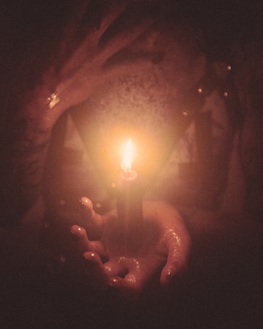 a witch holding a black candle in their hands