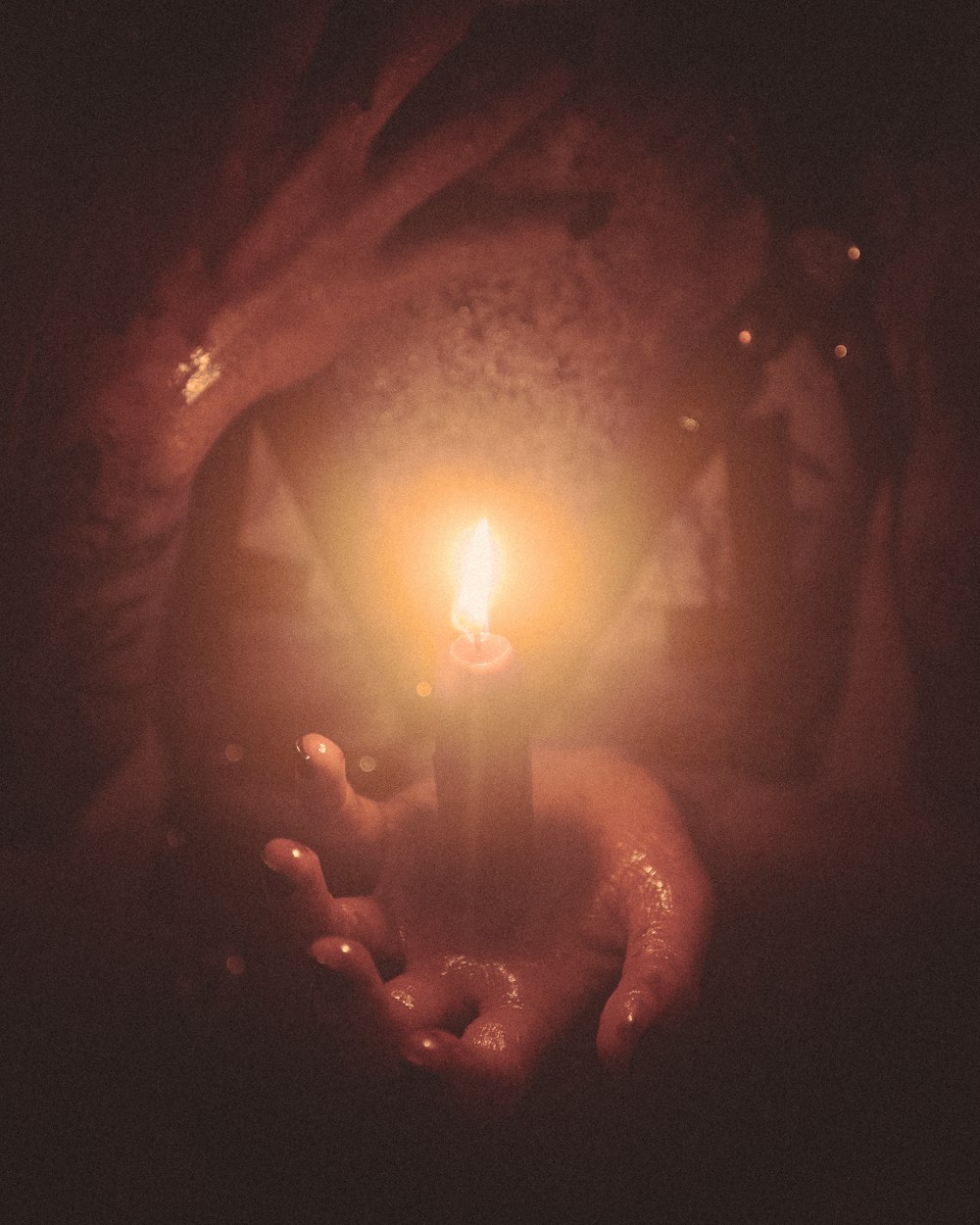 a person holding a lit candle in their hands