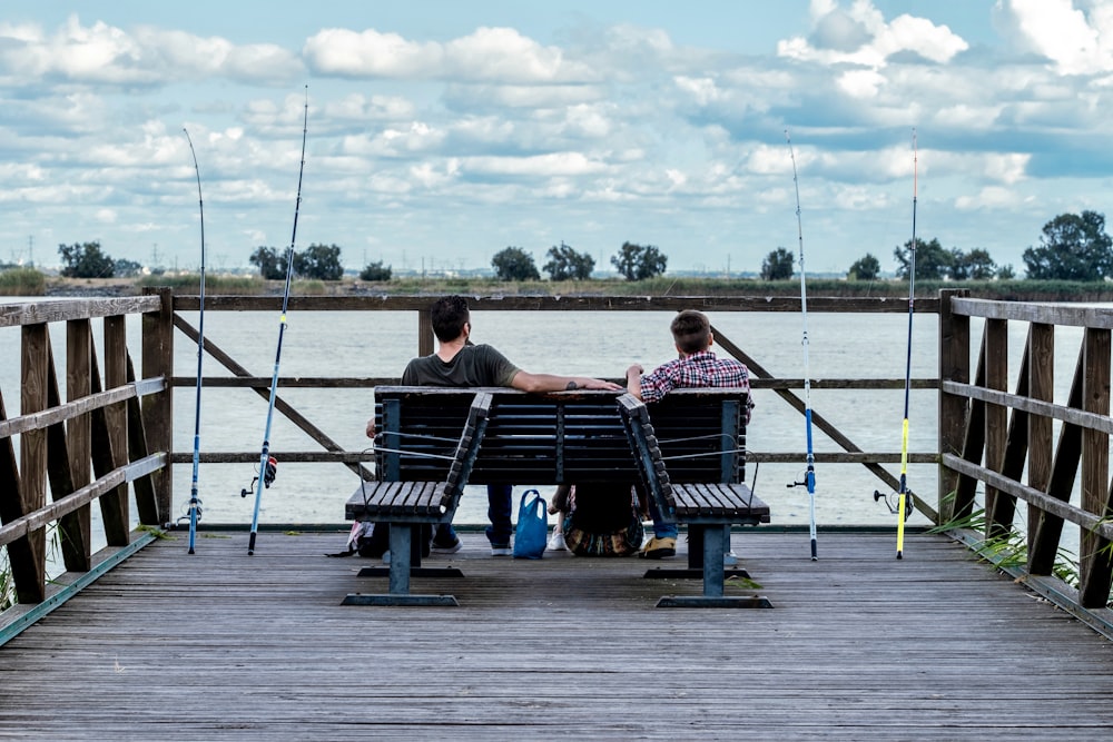 two people sitting on a bench on a pier