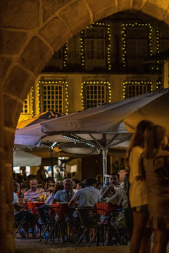 A vibrant scene of members enjoying a beautifully set outdoor dinner under string lights, with chefs presenting dishes.