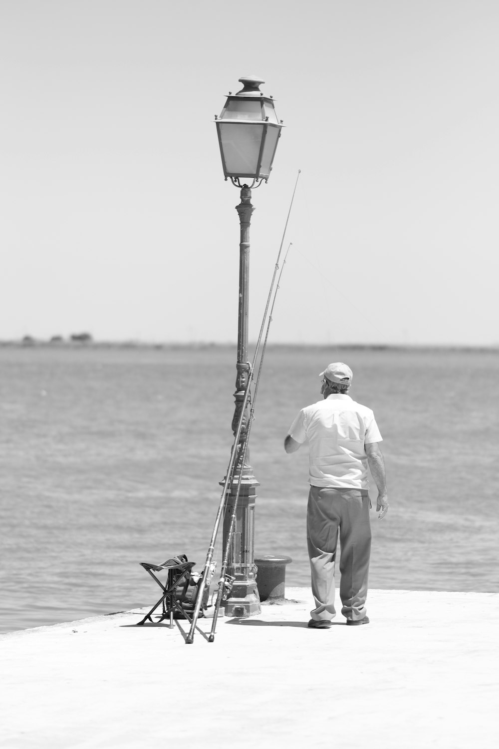 a man standing on a pier next to a light pole