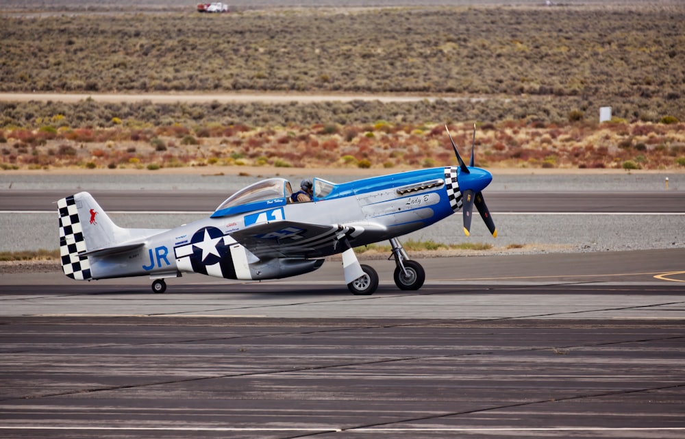 a small blue and white airplane on a runway