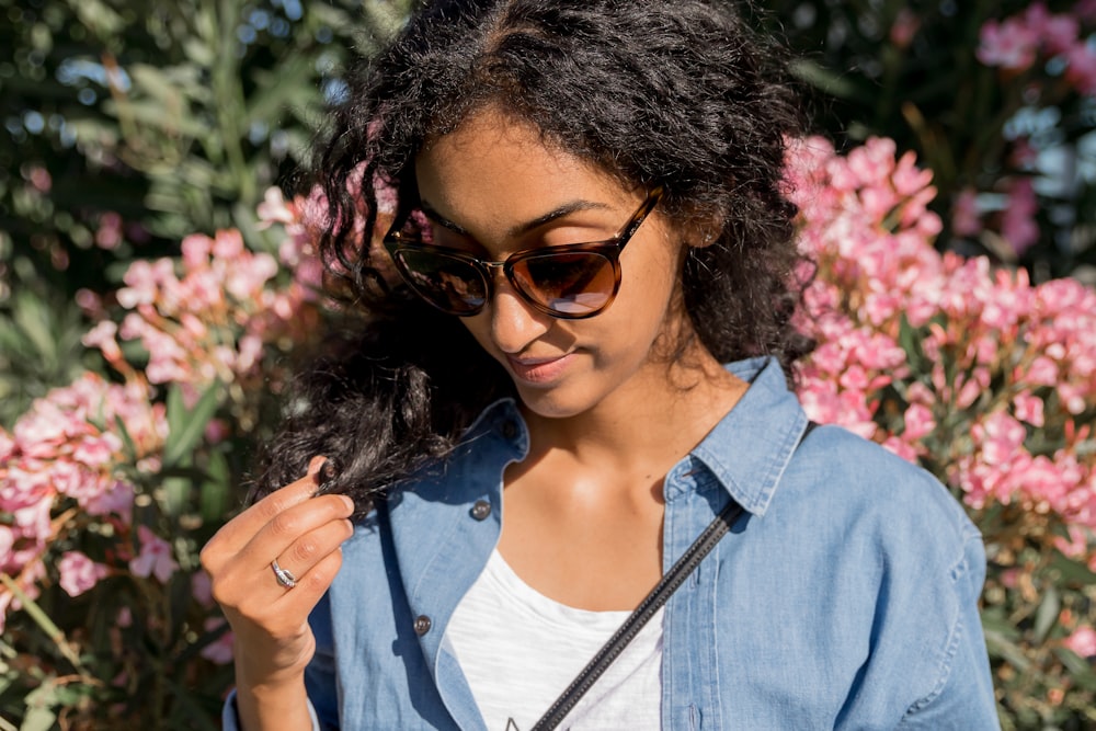 a woman in a denim shirt looking down at her cell phone