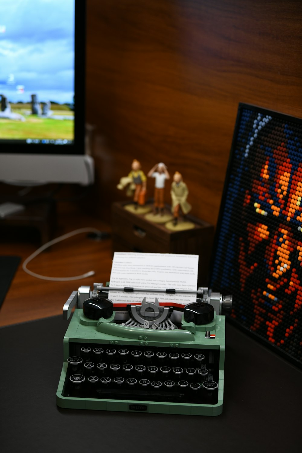 a green typewriter sitting on top of a desk next to a monitor