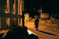 Nighttime patrol with a security guard walking along a well-lit perimeter fence.