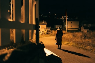 Nighttime patrol with a security guard walking along a well-lit perimeter fence.