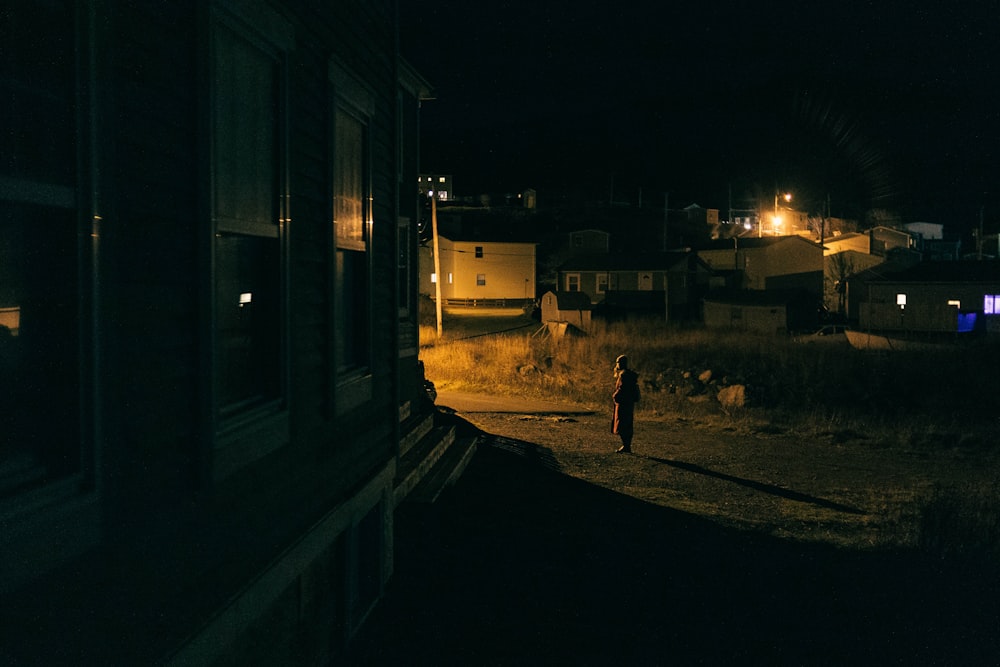 a person standing in the dark near a building